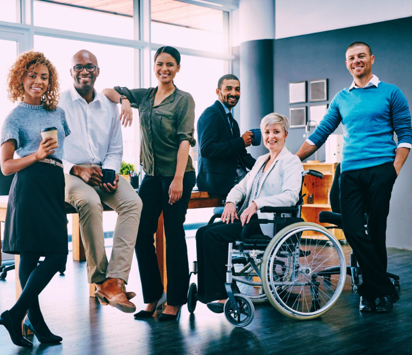 7 principais barreiras que impedem a inclusão 3 Colegas de trabalho posam para foto sorrindo no escritório