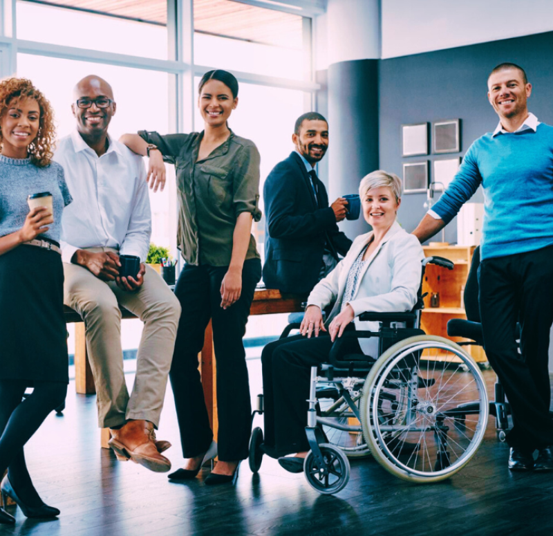 Colegas de trabalho posam para foto sorrindo no escritório